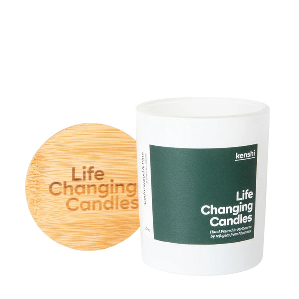 Candle with a wooden lid labeled 'Life Changing Candles' and a white container with a green label on a white background.