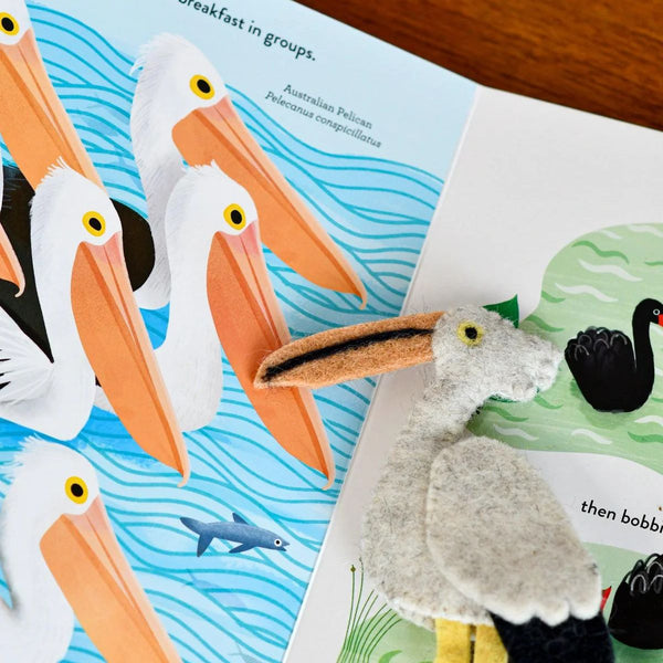 Felt finger puppet pelican next to educational book about pelicans and swans
