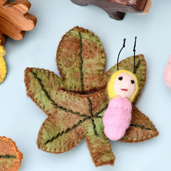 Felt figurine resting on an autumn-coloured chestnut felted leaf