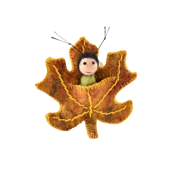 Felted toy of a caterpillar-like figurine inside a maple leaf on a white background