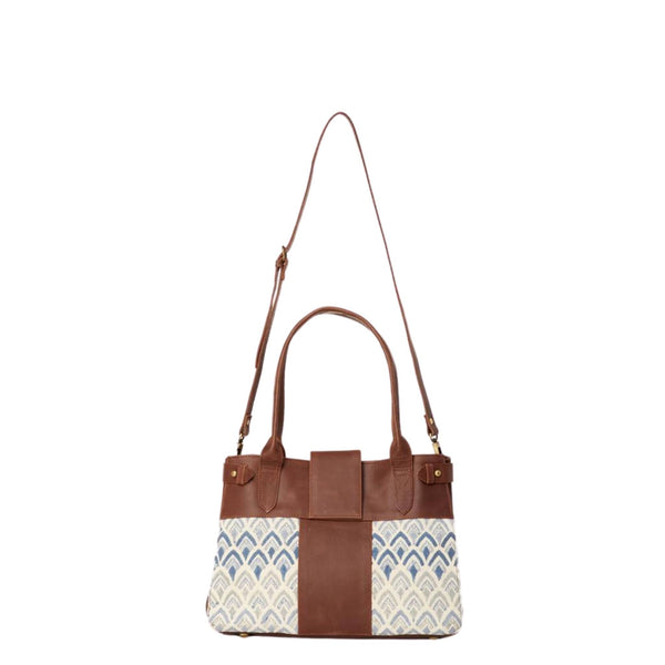 Handbag with hand-blockprinted cotton with blue print and brown leather exterior with paddle handles and expandable side straps shown with removable shoulder strap